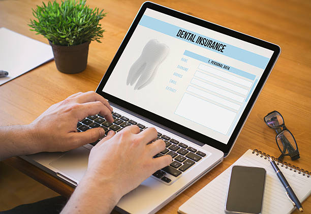 Image of person typing at the computer with Dental Insurance on the screen.